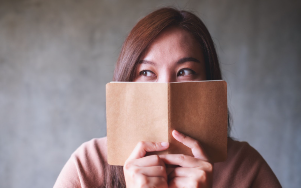 A woman's hiding behind a book